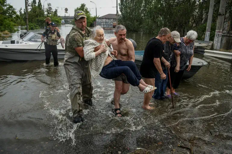 Ukrainian woman being rescued from the flood by a solider and people due to Explosion at Kakhovka Dam that can Sparks Ecological Disaster 